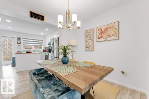 Dining area featuring wood-finish flooring, a contemporary chandelier, and an open layout to the kitchen - 53 1110 Daniels Link Link, Edmonton, AB - Indoor Photo Showing Dining Room