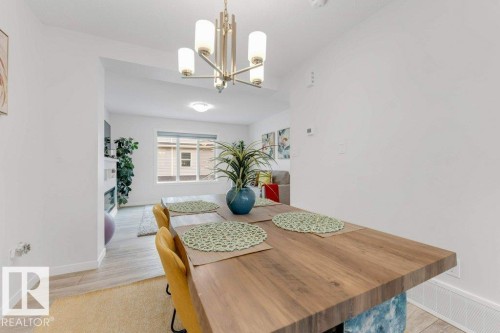 Dining area featuring a contemporary chandelier, wood-finish flooring, and white baseboards - 53 1110 Daniels Link Link, Edmonton, AB - Indoor Photo Showing Dining Room