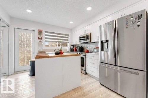 Bright kitchen featuring white cabinetry, stainless steel appliances, a center island with wood-finish countertop, recessed lighting, and light wood-finish flooring - 53 1110 Daniels Link Link, Edmonton, AB - Indoor Photo Showing Kitchen With Stainless Steel Kitchen