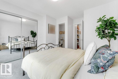 Carpeted bedroom featuring a mirrored sliding closet door, white walls, and two visible doorways - 53 1110 Daniels Link Link, Edmonton, AB - Indoor Photo Showing Bedroom