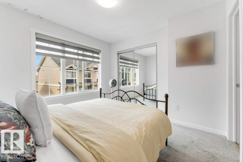 Bright room with neutral wall paint, grey carpeting, a large window featuring horizontal blinds, and mirrored closet doors - 53 1110 Daniels Link Link, Edmonton, AB - Indoor Photo Showing Bedroom