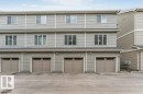 Multi-story building exterior featuring gray horizontal siding and individual garage doors - 53 1110 Daniels Link Link, Edmonton, AB  - Outdoor With Facade 
