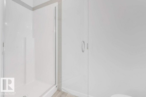 Walk-in shower enclosure with a white acrylic surround, clear glass door, and chrome hardware - 53 1110 Daniels Link Link, Edmonton, AB - Indoor Photo Showing Bathroom