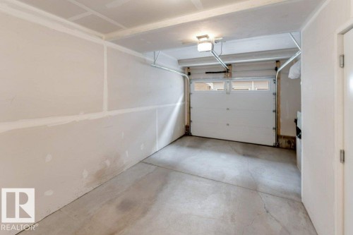 Single-car garage with a concrete floor, equipped with an overhead door featuring upper window panels, and interior lighting - 53 1110 Daniels Link Link, Edmonton, AB - Indoor Photo Showing Garage