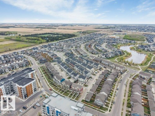 Expansive community featuring diverse residential architecture, a prominent central lake with surrounding pathways, and multiple apartment buildings - 53 1110 Daniels Link Link, Edmonton, AB - Outdoor With View