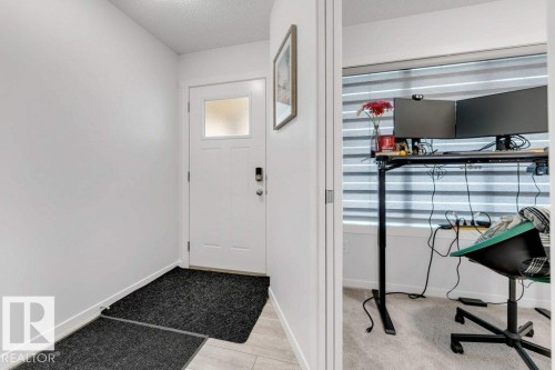 Entryway with a white paneled door featuring an integrated window, a smart lock, and light-toned tile flooring - 53 1110 Daniels Link Link, Edmonton, AB - Indoor