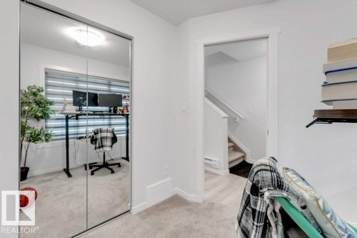 Mirrored closet doors featuring a bright interior reflection, light-toned wall finishes, and a doorway opening to a carpeted staircase - 53 1110 Daniels Link Link, Edmonton, AB - Indoor