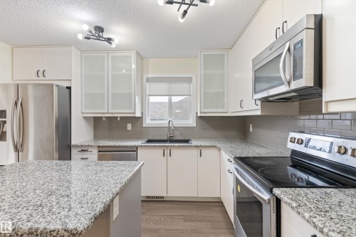 Kitchen featuring white cabinetry, granite countertops, stainless steel appliances, a subway tile backsplash, and wood-finish flooring - 336 Watt Boulevard, Edmonton, AB - Indoor Photo Showing Kitchen With Upgraded Kitchen