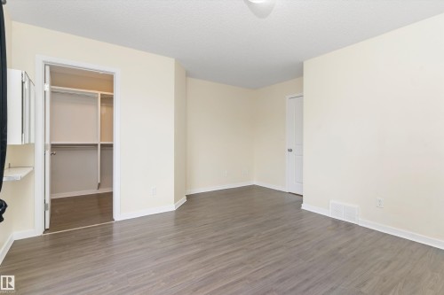 Spacious room featuring wood-finish flooring, light-toned walls, and a built-in closet with shelving and hanging rods - 336 Watt Boulevard, Edmonton, AB - Indoor Photo Showing Other Room