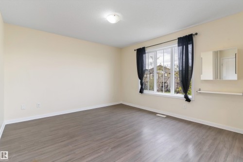 Bright room featuring wood-finish flooring, a large multi-pane window, and a built-in mirrored cabinet with an integrated shelf - 336 Watt Boulevard, Edmonton, AB - Indoor Photo Showing Other Room