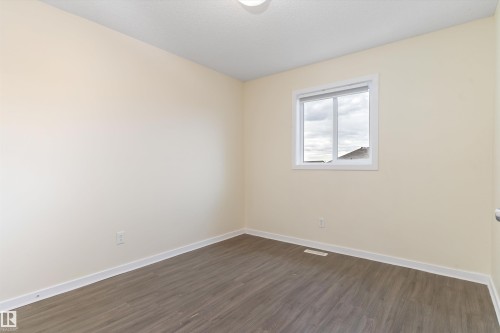 Neutral-toned room featuring wood-finish flooring, white baseboards, and a single window with white trim - 336 Watt Boulevard, Edmonton, AB - Indoor Photo Showing Other Room