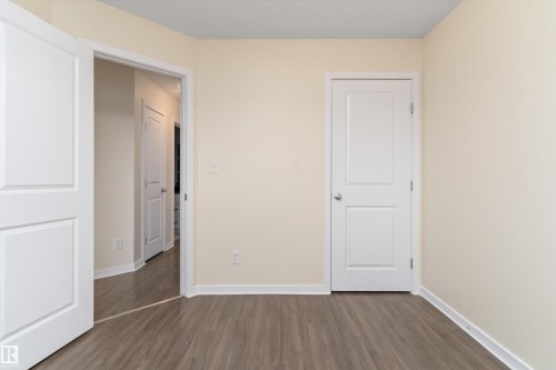 Room featuring wood-finish flooring, light-colored walls, white baseboards, and two white paneled doors - 336 Watt Boulevard, Edmonton, AB - Indoor Photo Showing Other Room