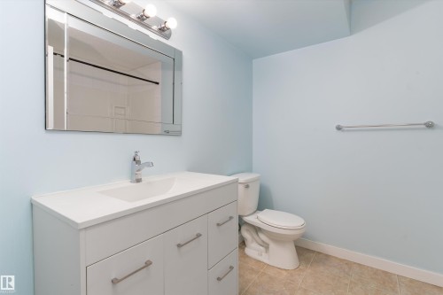 Bathroom featuring a modern white vanity with an integrated sink, a chrome faucet, and a large wall-mounted mirror with overhead lighting - 336 Watt Boulevard, Edmonton, AB - Indoor Photo Showing Bathroom