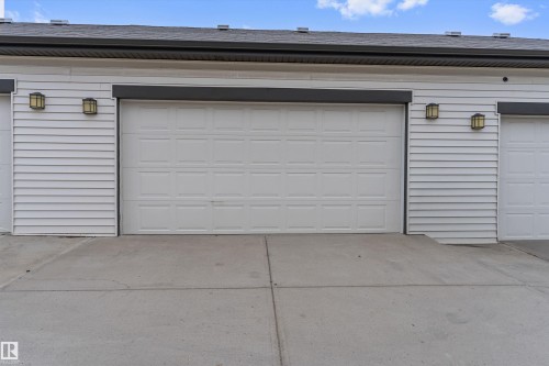 Attached garage featuring a panel-style door, horizontal siding, and two exterior wall sconces - 336 Watt Boulevard, Edmonton, AB - Outdoor With Exterior