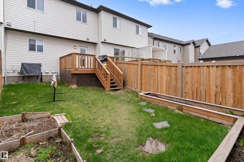 Private backyard featuring a wooden deck with railing and stairs, a wooden privacy fence, raised garden beds, and stepping stones - 336 Watt Boulevard, Edmonton, AB - Outdoor With Exterior