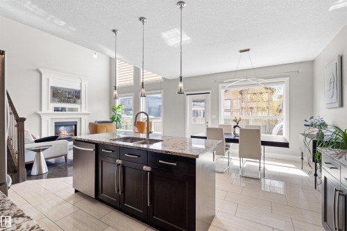 Open-concept kitchen featuring an island with a double basin sink, stainless steel appliances, and pendant lighting - 3807 Claxton Close, Edmonton, AB - Indoor Photo Showing Kitchen With Double Sink With Upgraded Kitchen