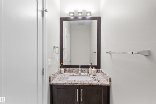 Bathroom vanity featuring a granite countertop, undermount sink, dark wood-finish cabinetry, and a framed mirror - 3807 Claxton Close, Edmonton, AB - Indoor Photo Showing Bathroom