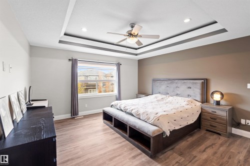 Spacious room featuring wood-finish flooring, a tray ceiling with recessed lighting and a ceiling fan, and a large window with curtain rods - 3807 Claxton Close, Edmonton, AB - Indoor Photo Showing Bedroom