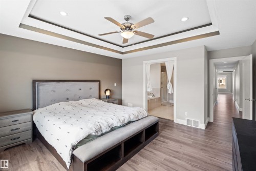 Spacious bedroom featuring wood-finish flooring and a tray ceiling with recessed lighting - 3807 Claxton Close, Edmonton, AB - Indoor Photo Showing Bedroom