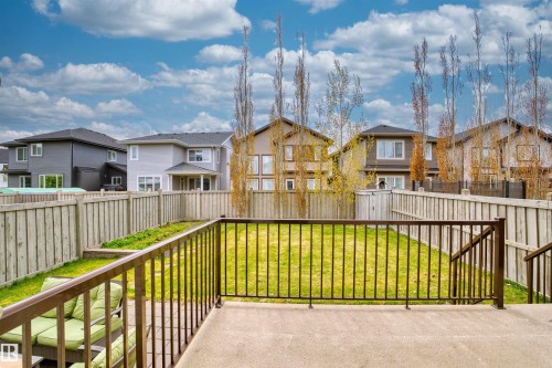 Spacious fenced backyard featuring a concrete patio, wrought iron railing, and manicured lawn - 3807 Claxton Close, Edmonton, AB - Outdoor