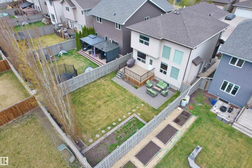 Rear exterior featuring a spacious fenced yard, elevated deck with dark railings, and a ground-level patio with stone pavers - 3807 Claxton Close, Edmonton, AB - Outdoor With Deck Patio Veranda