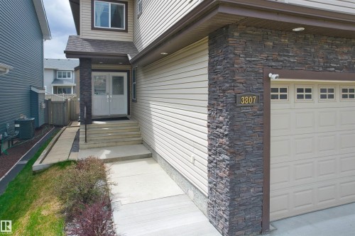 Exterior facade featuring stacked stone accents, horizontal siding, and a double-door entry - 3807 Claxton Close, Edmonton, AB - Outdoor With Exterior