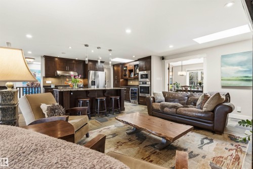 Open-concept living space featuring a gourmet kitchen with dark wood cabinetry, stainless steel appliances, and a central island with bar seating - 9010 120 Street, Edmonton, AB - Indoor Photo Showing Living Room