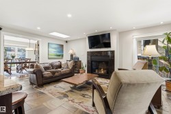 Living area featuring large format stone tile flooring, a dark stone fireplace surround, an inset fireplace, and recessed lighting - 