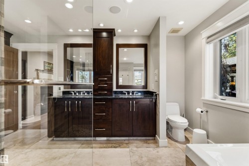 Bathroom featuring a spacious double vanity with dark wood cabinetry, dark countertops, and dual mirrors - 9010 120 Street, Edmonton, AB - Indoor Photo Showing Bathroom
