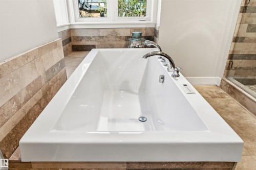 White rectangular soaking tub with polished chrome fixtures, integrated controls, and a window above - 9010 120 Street, Edmonton, AB - Indoor Photo Showing Bathroom