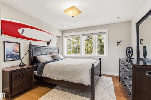 Bedroom featuring a dark wood bed frame with a slatted headboard, wood-finish flooring, two large windows, and a built-in recessed shelf - 9010 120 Street, Edmonton, AB - Indoor Photo Showing Bedroom