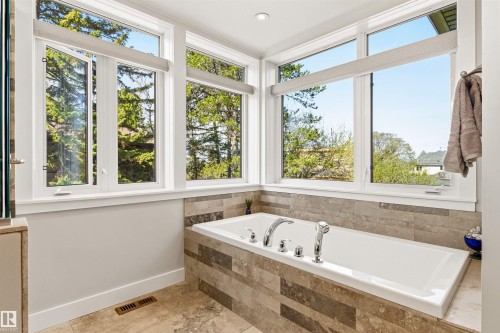 Soaking tub with chrome fixtures, surrounded by a tiled enclosure and large windows - 9010 120 Street, Edmonton, AB - Indoor Photo Showing Bathroom