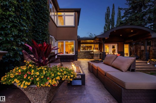 Spacious concrete patio featuring a built-in fire pit, stone-clad walls, and a curved patio cover with recessed lighting - 9010 120 Street, Edmonton, AB - Outdoor With Deck Patio Veranda