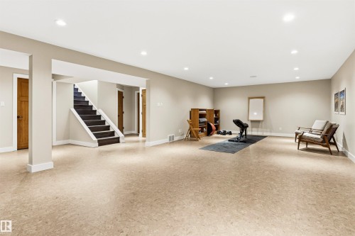 Spacious finished basement featuring recessed lighting, a carpeted staircase with white risers, light-colored walls, and solid core doors with dark hardware - 9010 120 Street, Edmonton, AB - Indoor