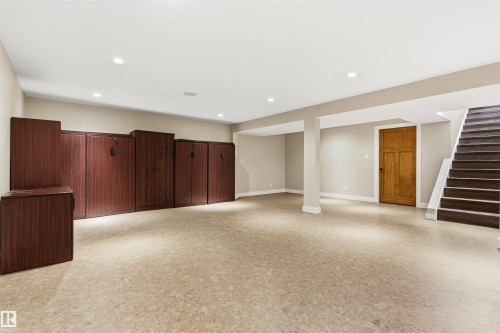 Spacious lower level featuring light-toned resilient flooring, recessed ceiling lighting, and a full wall of wood-finish built-in cabinetry - 9010 120 Street, Edmonton, AB - Indoor