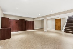Spacious lower level featuring light-toned resilient flooring, recessed ceiling lighting, and a full wall of wood-finish built-in cabinetry - 