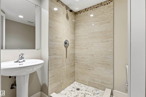 Walk-in shower with natural stone-look tiling and pebble floor detailing - 9010 120 Street, Edmonton, AB - Indoor Photo Showing Bathroom