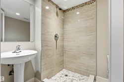 Walk-in shower with natural stone-look tiling and pebble floor detailing - 