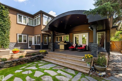 Rear exterior featuring a large covered patio with stone columns and dual-pane doors - 9010 120 Street, Edmonton, AB - Outdoor With Deck Patio Veranda