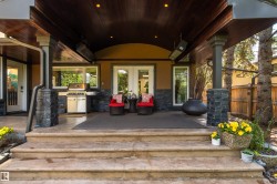Covered outdoor patio featuring a wood-finish ceiling, recessed lighting, and stone veneer columns - 