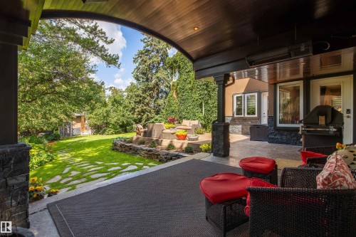 Covered patio featuring a wood-finish ceiling, stone columns, and an integrated outdoor heater - 9010 120 Street, Edmonton, AB - Outdoor With Deck Patio Veranda