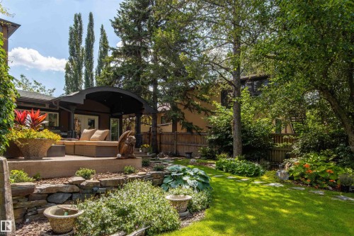 Expansive backyard featuring a manicured lawn, established plantings, and a multi-level hardscaped patio - 9010 120 Street, Edmonton, AB - Outdoor With Deck Patio Veranda