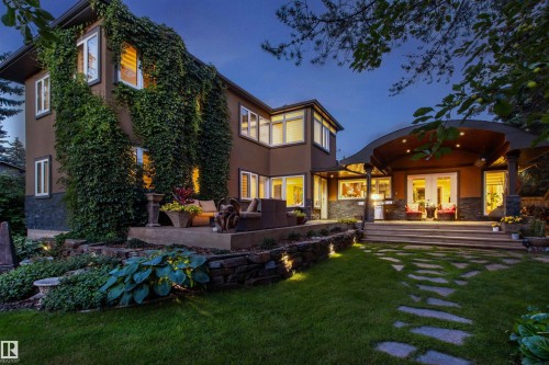 Exterior featuring a stone patio, extensive landscaping, and a manicured lawn with stepping stones - 9010 120 Street, Edmonton, AB - Outdoor With Deck Patio Veranda