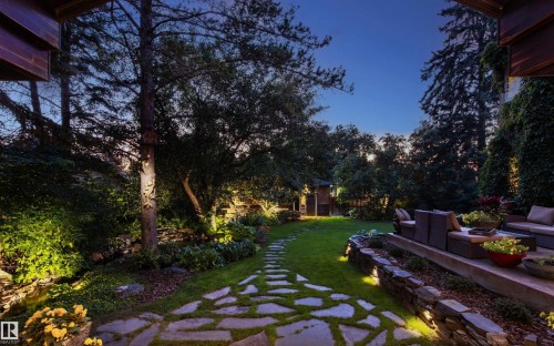 Expansive backyard featuring a natural stone pathway, manicured lawn, and mature trees - 9010 120 Street, Edmonton, AB - Outdoor