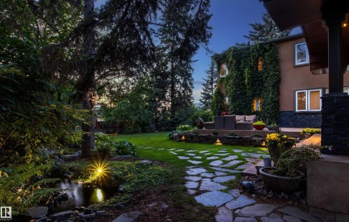 Landscaped backyard featuring a stone patio, flagstone pathway, and a water feature - 9010 120 Street, Edmonton, AB - Outdoor