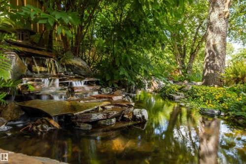 Stone waterfall feature with cascading water into a reflective pond - 9010 120 Street, Edmonton, AB - Outdoor