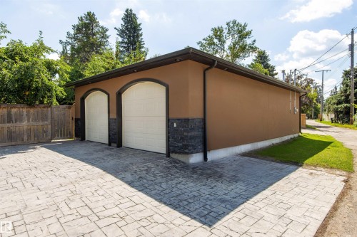 Detached garage with two arched overhead doors, stucco exterior, and stone veneer accents - 9010 120 Street, Edmonton, AB - Outdoor With Exterior