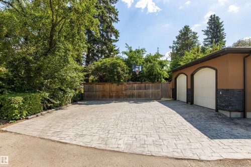 Stamped concrete driveway leading to a two-car garage with arched doors - 9010 120 Street, Edmonton, AB - Outdoor