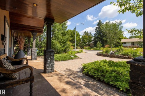 Covered front porch with wood-finish ceiling, recessed lighting, and stone-clad columns - 9010 120 Street, Edmonton, AB - Outdoor With Deck Patio Veranda
