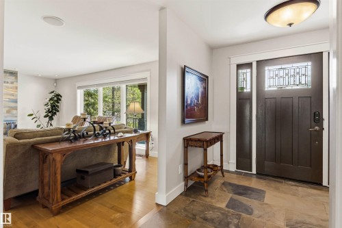 Entryway featuring a dark wood door with leaded glass transom and sidelight, large format stone tile flooring, and a flush mount ceiling light - 9010 120 Street, Edmonton, AB - Indoor Photo Showing Other Room